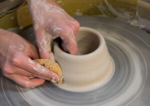 Hands working with clay on potters wheel