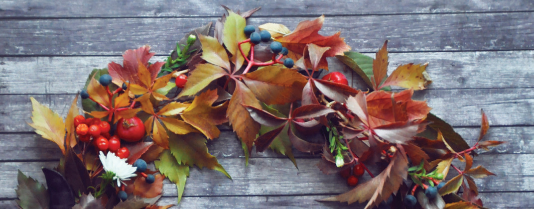 Top section of a fall wreath hanging on a wooden wall