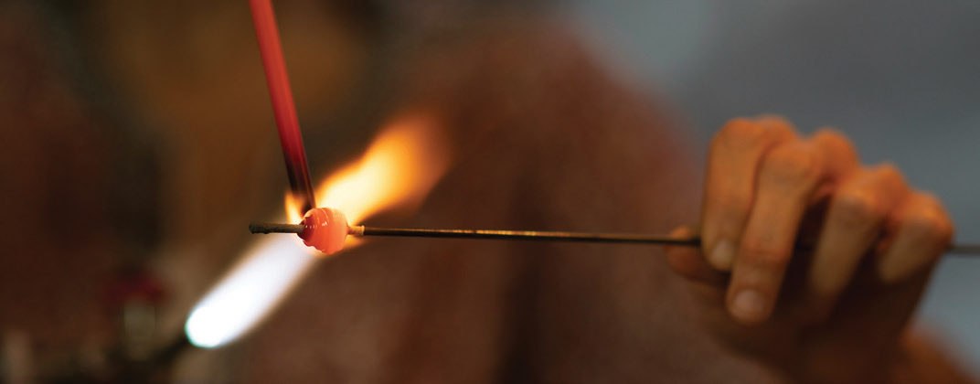 Close up of person's hands working on glass using a torch