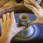 Close up of hands creating a vase on a pottery wheel